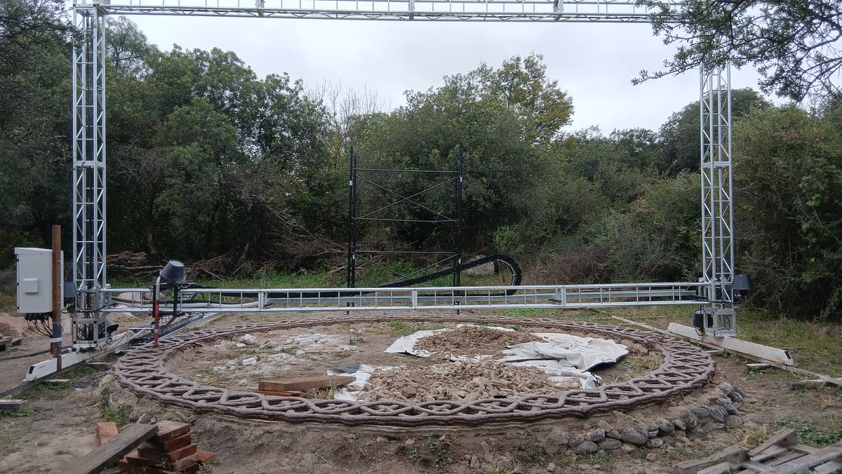 Las primeras hiladas del muro impresas sobre el terreno, con el pórtico de la impresora montado encima